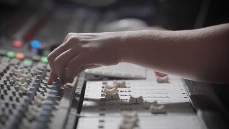 sound engineer is reducing signals from sources and applying effects on a recorded sound in a studio