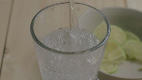 vertiendo un vaso de refrescante agua con gas con rodajas de lima