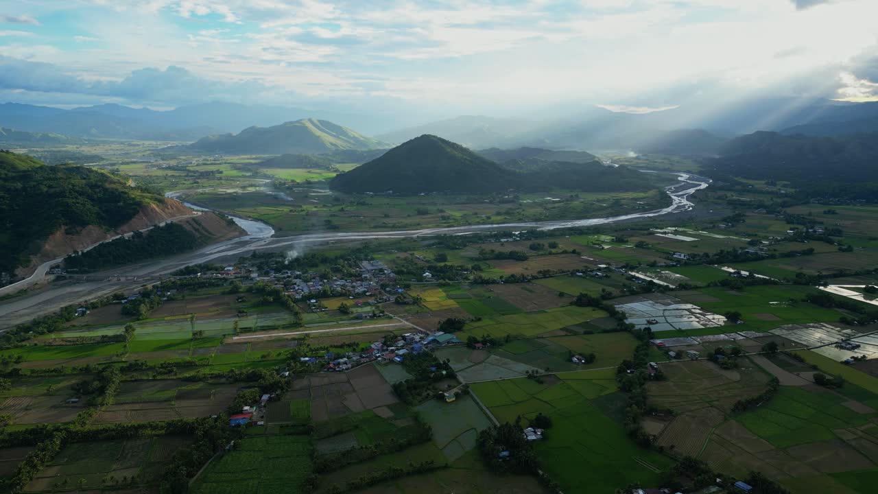 A high wide aerial of Bagabag reveals patchwork rice fields, scattered rooftops, and lush mountain edges of Bagabag, Nueva Vizcaya, Philippines