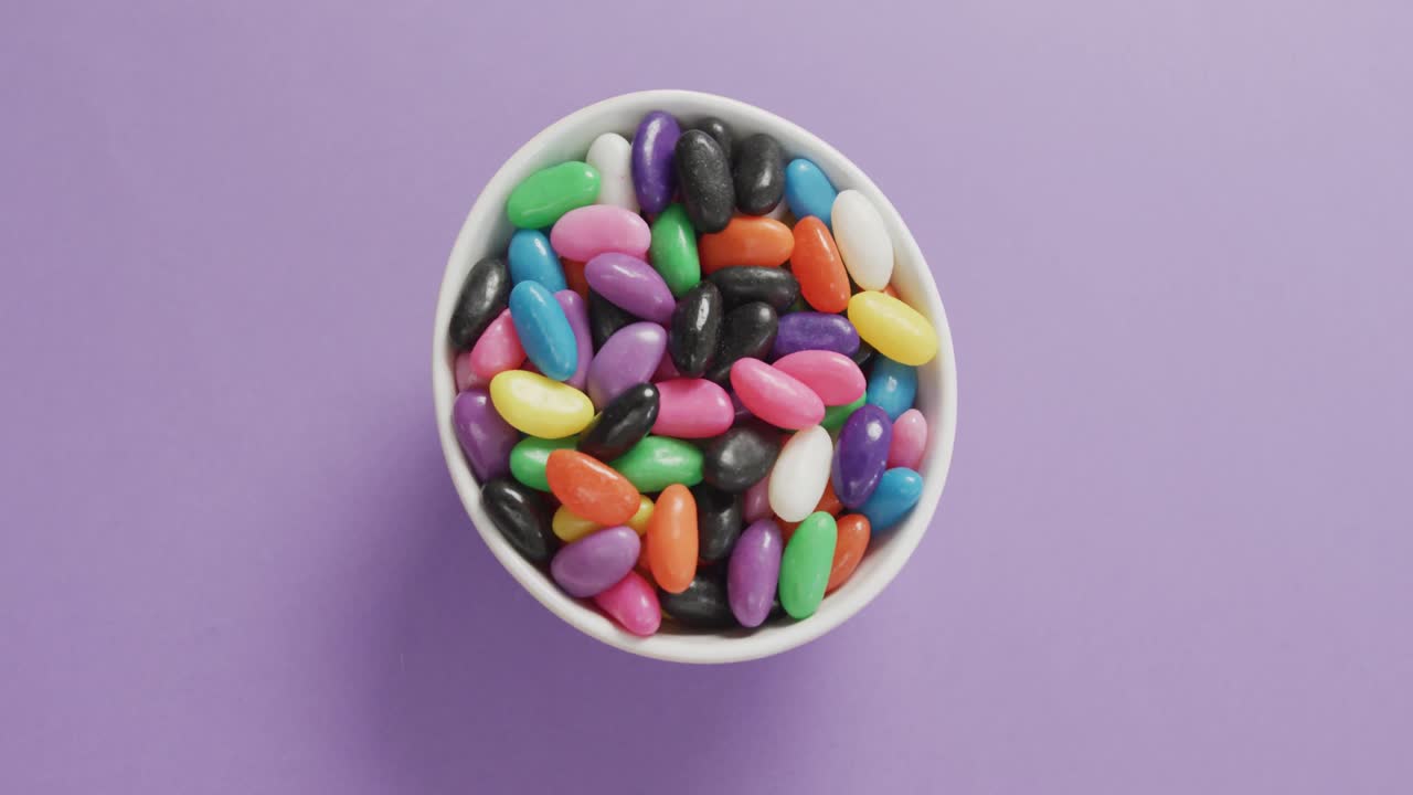 video de primer plano de dulces multicolores en un cuenco sobre un fondo púrpura