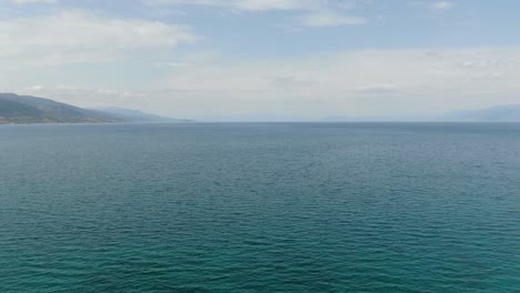 Drone-view-in-Albania-flying-over-Ohrid-lake-top-view-crystal-clear-water-and-green-mountains