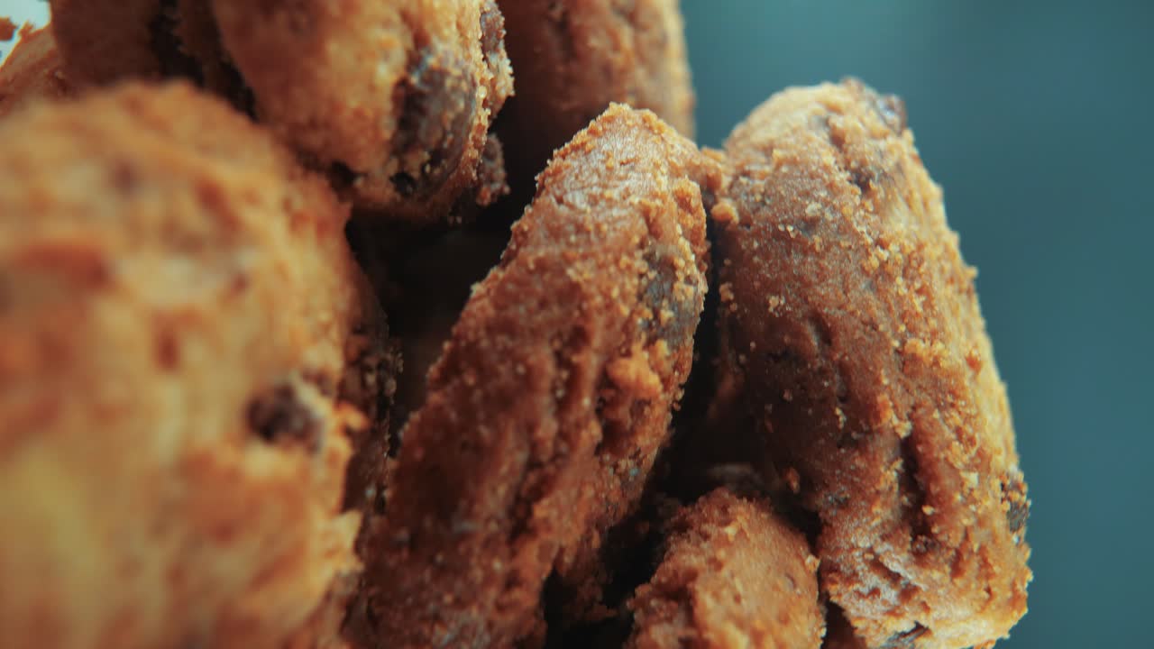 una toma cinematográfica macro vertical de una pila llena de galletas de chocolate crujientes y jugosas, en un soporte giratorio, iluminación de estudio, cámara lenta, movimiento suave, video 4k