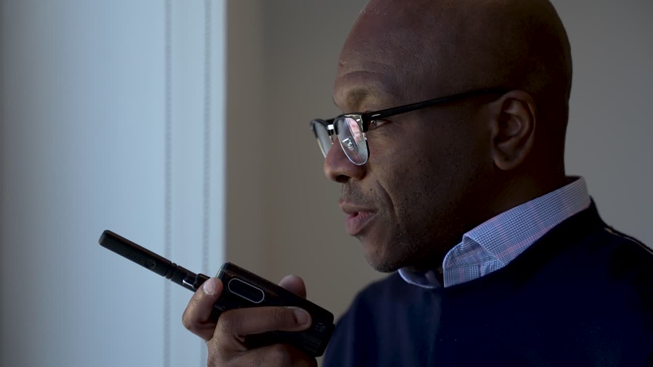 Black Businessman communicating through a walkie talkie in a modern office setting