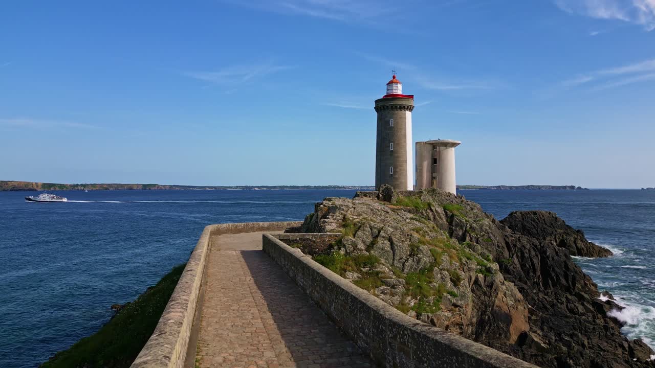 Scenic view of historic Petit Minou Lighthouse on rocky islet, stone tower, causeway, and blue sea with ferry, Brittany, France