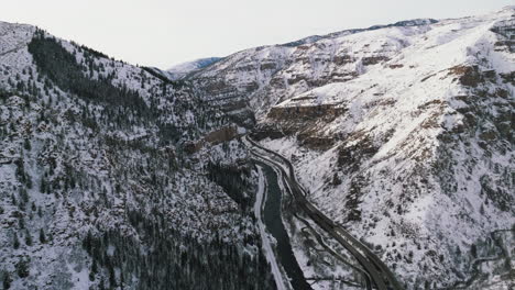 drone dolley tilt shot of colorado river streaming next to a highway through the glennwood canyon in winter