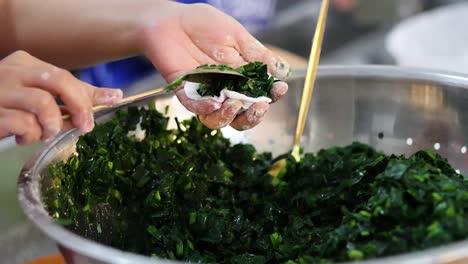 hands making stuffed vegetable rolls in kitchen