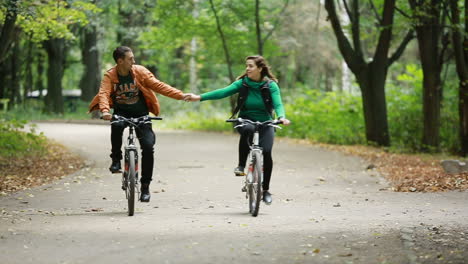 couple in love ride bicycles. happy funny young couple riding on bicycle in nature