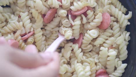 close-up of pasta with hot dogs being stirred