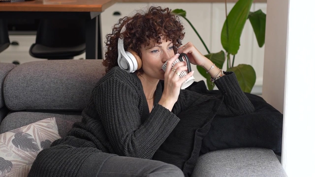 Una donna a suo agio si gode musica rilassante a casa mentre indossa cuffie comode