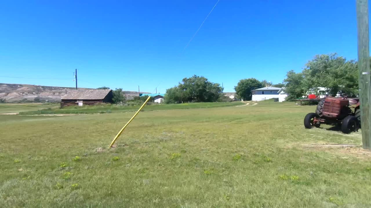 Passing by a farm in the country with farming equipment and old trucks on the land on a sunny day