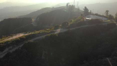 Aerial-Tilt-Up-Reveal-of-Hazy-Foothills-on-Verdant-Mountain