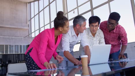 Multi-ethnic-business-colleagues-discussing-over-laptop-in-a-meeting-at-modern-office-4k