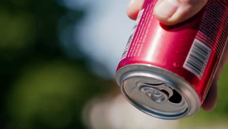Person opening a red soda can