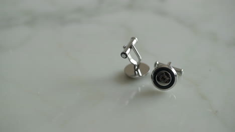 close up to a pair of cufflinks with one of them spinning in slow motion