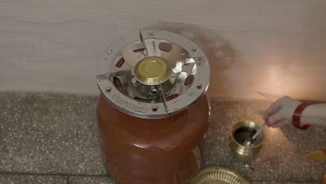 indian women prying liquefied petroleum gas cylinder or holy fire god with offerings at home