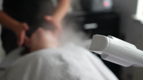 aesthetician beautician performing a facial treatment with a steam machine