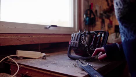 the man is maintaining his chainsaw for cutting trees into firewood in indre fosen, trondelag county, norway - close up