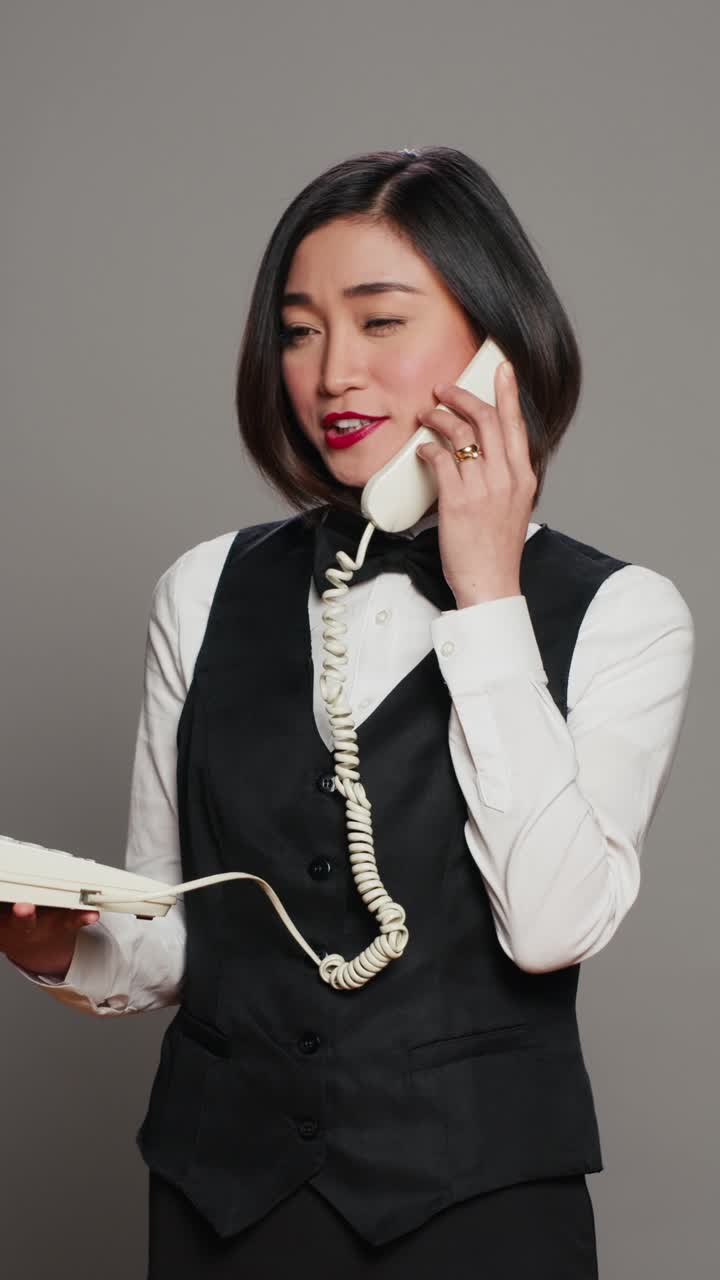 Video verticale di una receptionist asiatica che risponde a una telefonata in studio