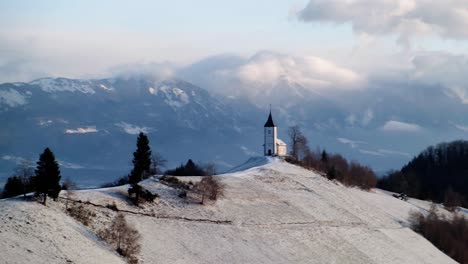 Blick-Auf-Die-Kirche-Von-Jamnik-In-Einer-Winterlandschaft-Mit-Farbenfrohem-Sonnenaufgang-In-Kranj,-Slowenien