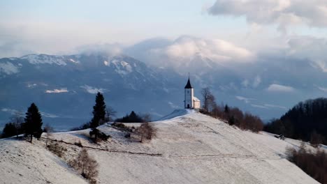 view of jamnik church in a winter landscape with colourful sunrise in kranj, slovenia