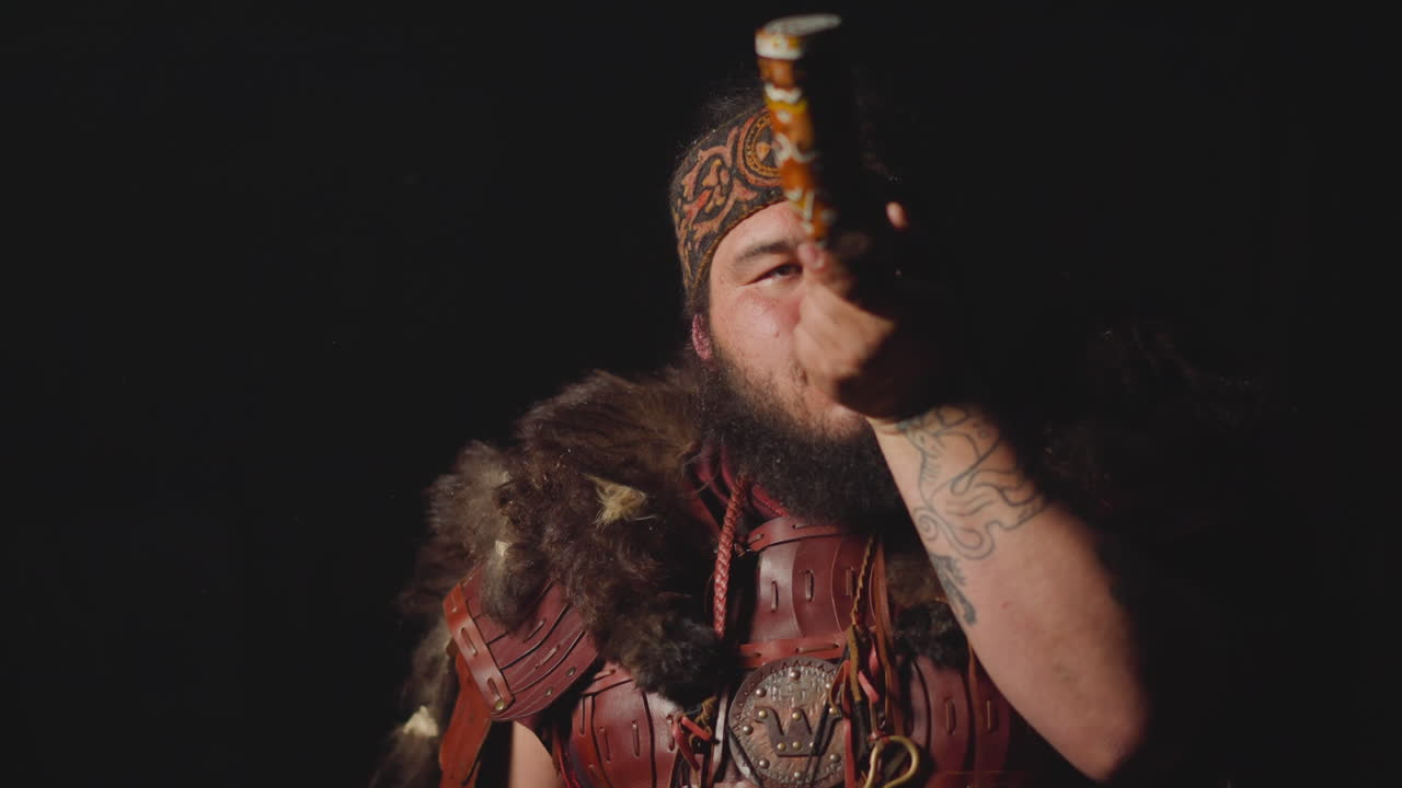 Obese man in ethnic leather costume smokes shaman pipe