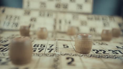 video macro de un tablero de bingo, luces de estudio, 120 fps, cámara lenta, dígitos de chips de madera, imágenes en bruto, juego de mesa de lotería, números de cartas, empuje de grúa en movimiento suave, pasar a través