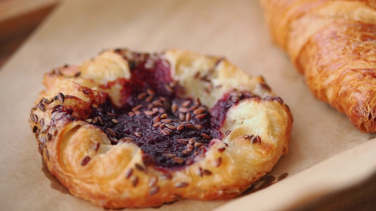 Hand Picking Up a Berry Danish Pastry from Parchment Paper