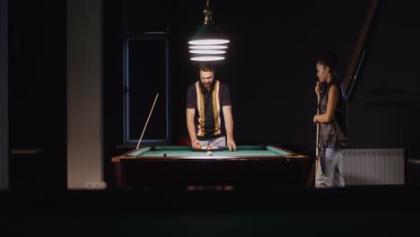 couple playing pool in a dark room