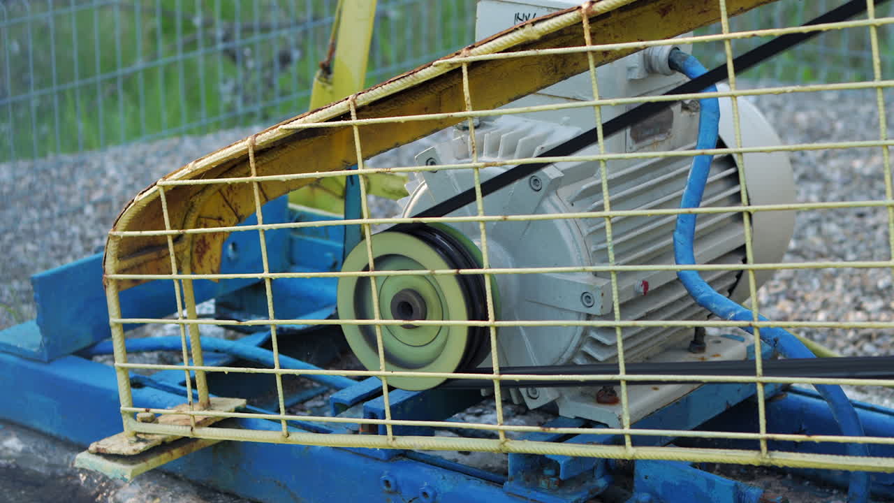 motore elettrico asincrono con cinghia di trasmissione della potenza che gira rapidamente in gabbia protettiva