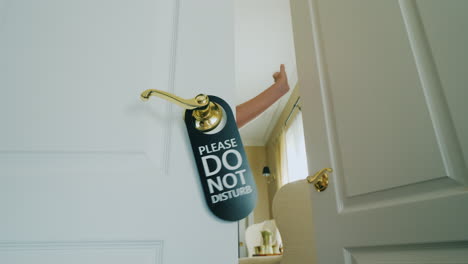 honeymoon in a luxury hotel - hand hangs on do not disturb sign on a wooden door