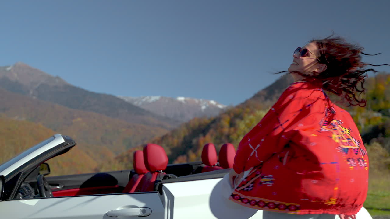 mujer en un coche convertible disfrutando de un pintoresco viaje por carretera de montaña