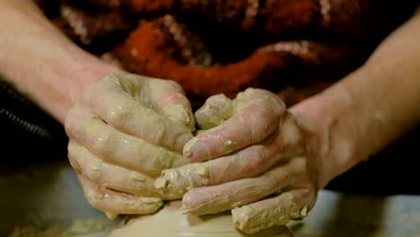 professional male potter working with clay on potter's wheel