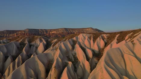 Paisaje-De-Capadocia-Con-Formaciones-De-Piedra-De-Toba-Durante-La-Puesta-De-Sol,-Revelación-Aérea-Delantera