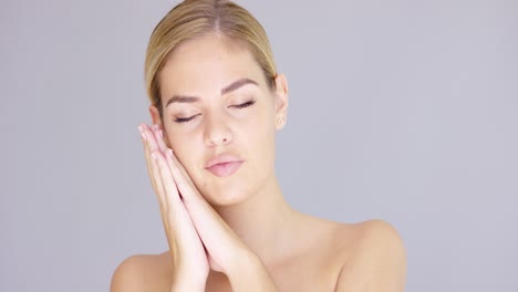 pretty young blond woman making a sleep gesture