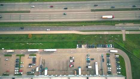 Warehouses,-huge-logistics-center-near-the-highway,-view-of-a-large-number-of-cargo-trailers-and-containers,-international-cargo-transportation,-aerial-view