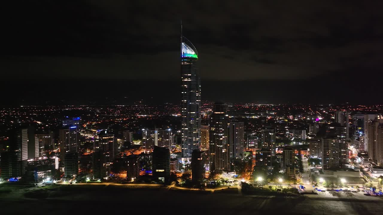 Gold Coast city downtown with residential tower and skyscrapers during night, drone panoramic.