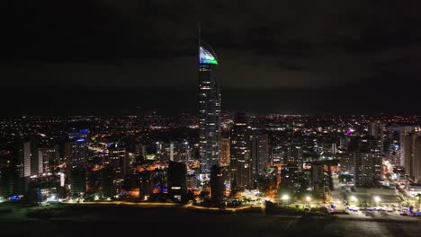 gold coast city downtown with residential tower and skyscrapers during night, drone panoramic.