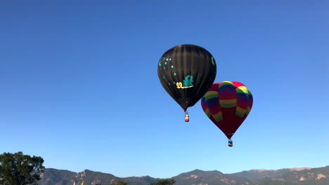 2 globos aerostáticos flotan juntos frente a las montañas