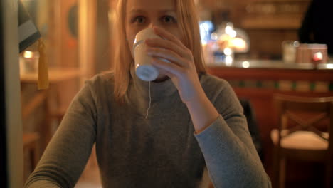 mujer usando almohadilla y tomando té en el café