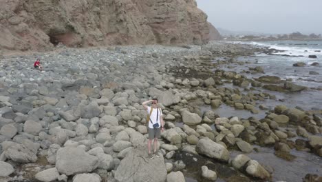 aerial-orbit-shot-of-a-young-white-male-traveling-and-exploring-by-himself-with-a-yellow-backpack-on-the-beaches-of-southern-California-dana-point