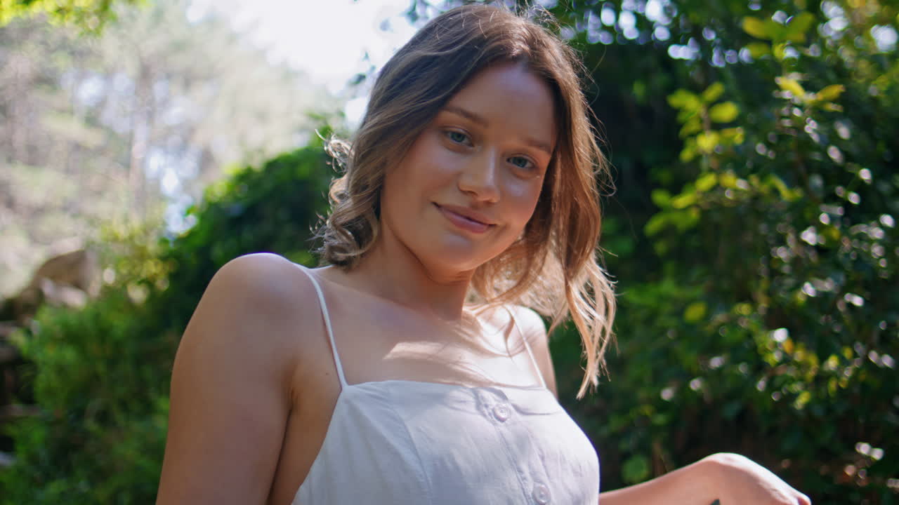 Tender lady enjoying nature looking camera in tranquil surroundings closeup