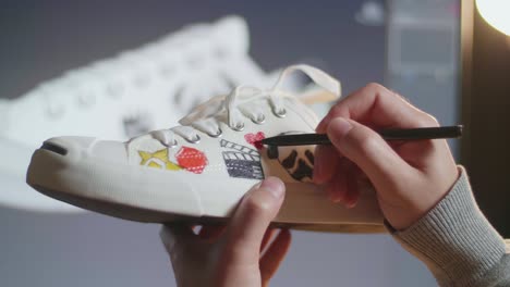 persona que personaliza un par de zapatos con diseños artísticos