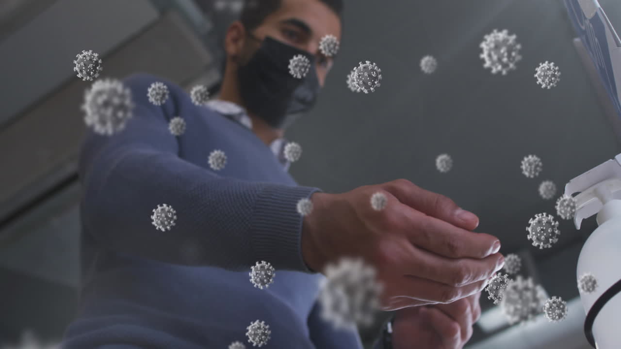 múltiples células de covid-19 flotando contra el hombre que usa máscara facial usando desinfectante de manos en la oficina