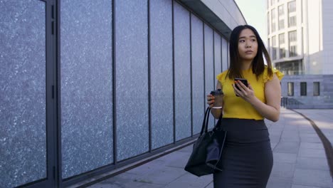 asian office worker using phone, drinking coffee