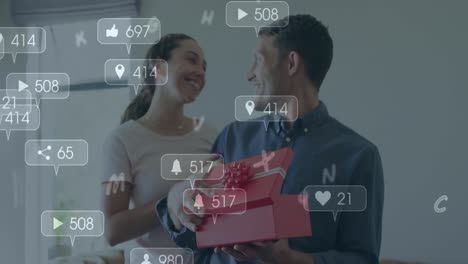 animación de iconos de las redes sociales sobre un hombre caucásico abriendo una caja regalada por su casa en casa.