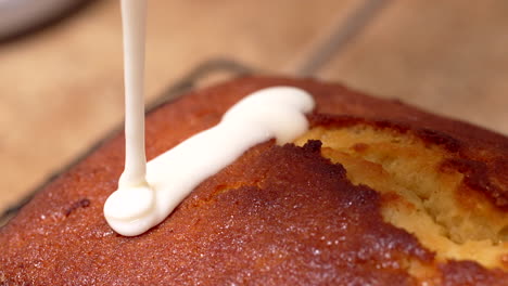 Drizzling-icing,-glaze-or-frosting-on-a-homemade-freshly-baked,-golden-brown-lemon-cake---slow-motion-deliciousness