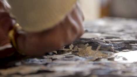 Close up of male hands cutting fabric with scissors - shallow depth of field with selective focus handheld interior shot natural light