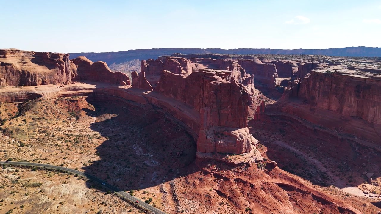 Splendido filmato stock del Parco Nazionale di Arches, USA, durante un pomeriggio luminoso. La luce solare brillante illumina le maestose strutture di arenaria rossa e il paesaggio desertico sotto un cielo azzurro limpido.