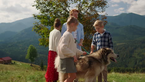 Friendly-people-walking-dog-on-green-hill.-Family-enjoying-holiday-with-pet.