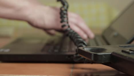 manos y dedos escribiendo en una computadora portátil mientras habla por teléfono plano medio